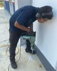 Man using a power drill during pest control or repair work.