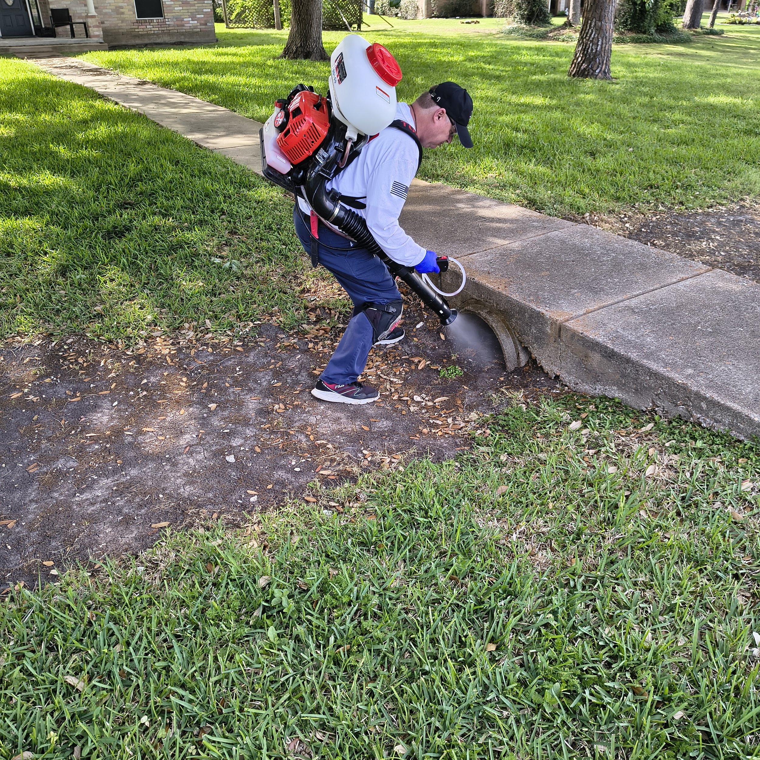 Technician working in a Fort Bend yard during a pest control service visit.