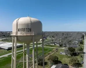 Wharton water tower under a clear sky, representing Texas Shield Pest Control’s extended coverage area.